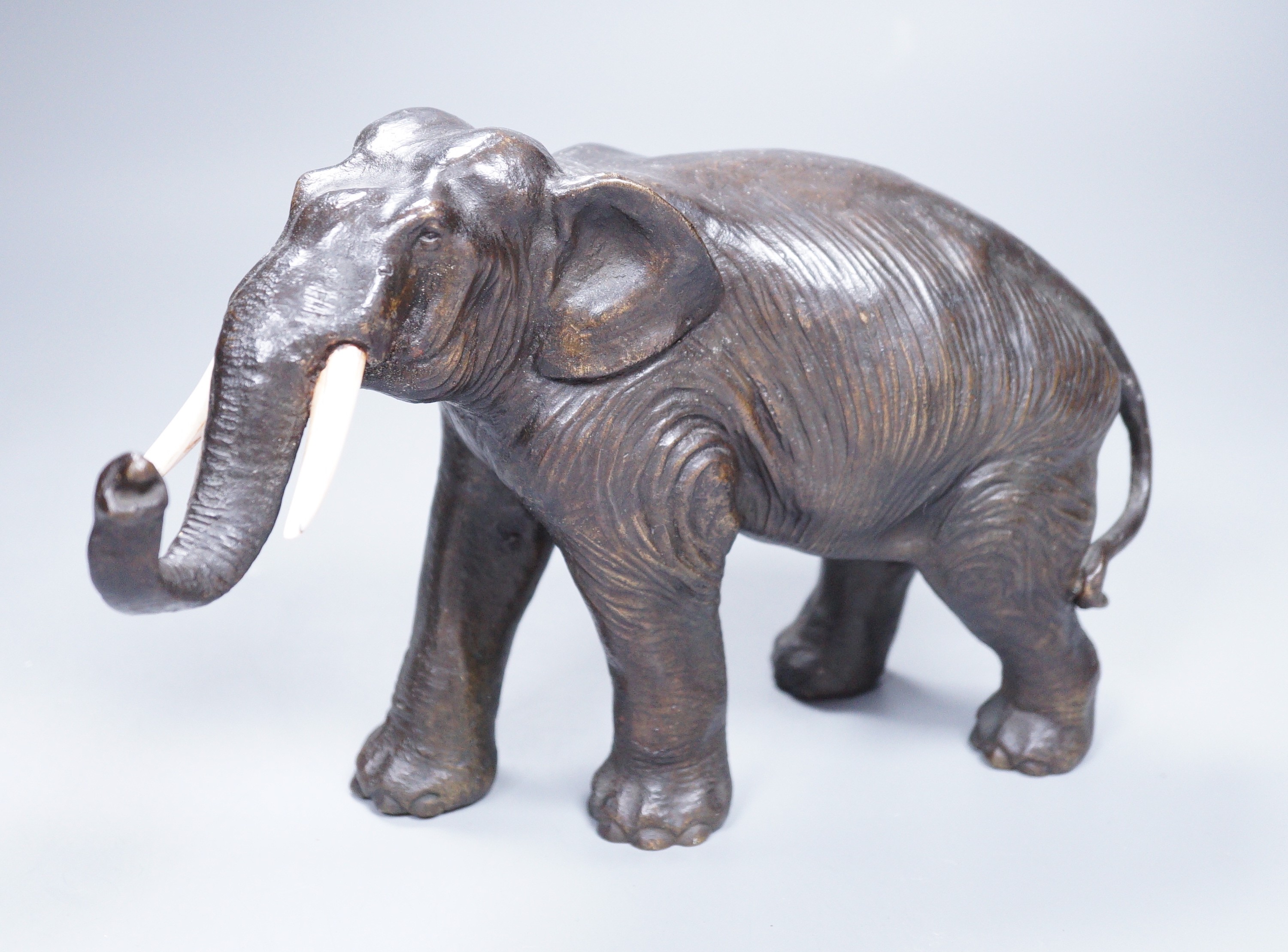 A Japanese Meiji period cast bronze model of an elephant, with ivory tusks, 17cm tall